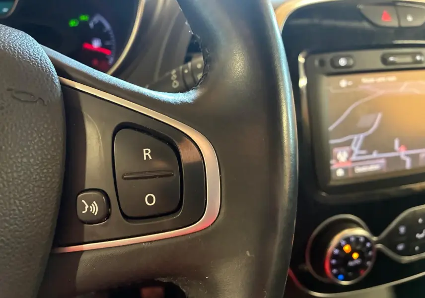 Gros plan sur le volant noir de la Renault Captur 1.5 DCI 90 Intens avec commandes vocales et écran GPS en arrière-plan.