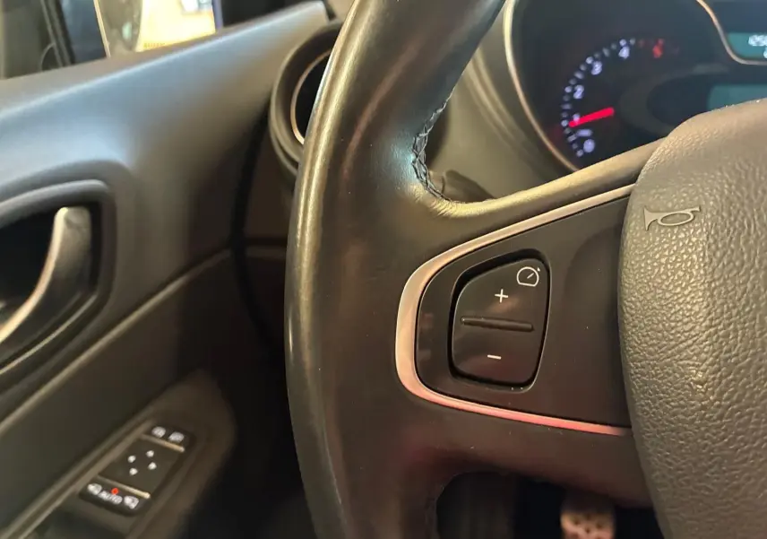 Gros plan sur le volant noir côté gauche du Renault Captur 1.5 DCI 90 Intens avec commandes intégrées et tableau de bord partiellement visible.