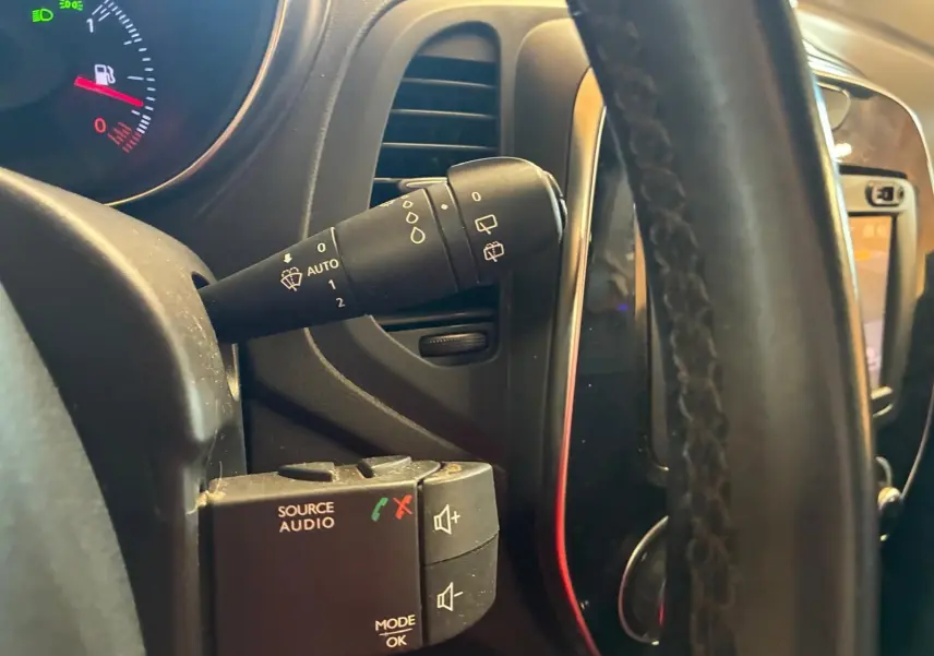 Gros plan sur la commande d’essuie-glace et les boutons audio derrière le volant du Renault Captur bleu 2017.