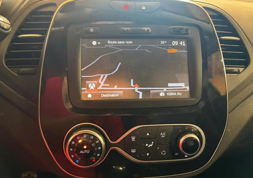 Vue rapprochée du tableau de bord noir du Renault Captur 2017 avec écran GPS et commandes de climatisation.