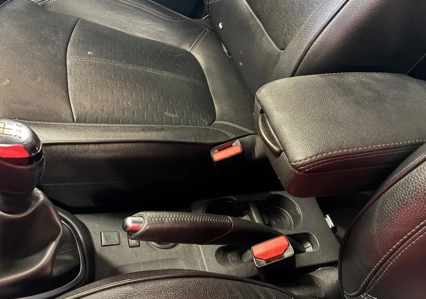 Gros plan intérieur sur la console centrale noire du Renault Captur bleu, montrant levier de vitesse manuel et frein à main.