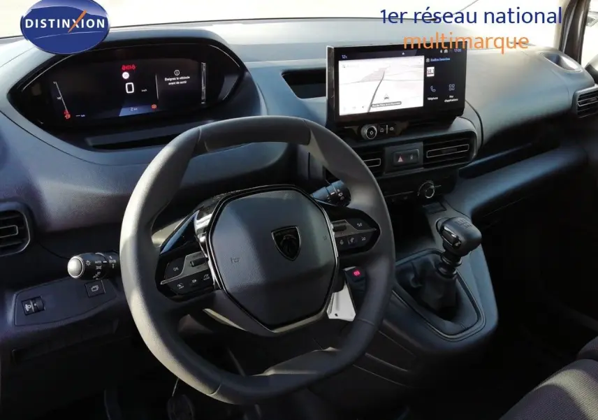 Vue intérieure du poste de conduite du Peugeot Partner blanc Kaolin 2026, avec volant multifonction et écran tactile central.