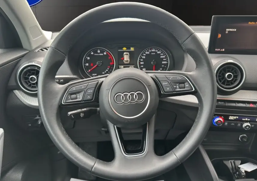 Vue intérieure centrée sur le volant Audi Q2 35 TFSI 2023 avec tableau de bord et écran multimédia visibles.