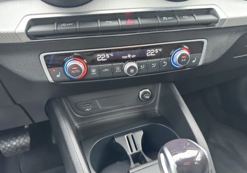 Vue rapprochée de la console centrale de l'Audi Q2 35 TFSI noir mito, montrant la climatisation automatique et le levier de vitesse.