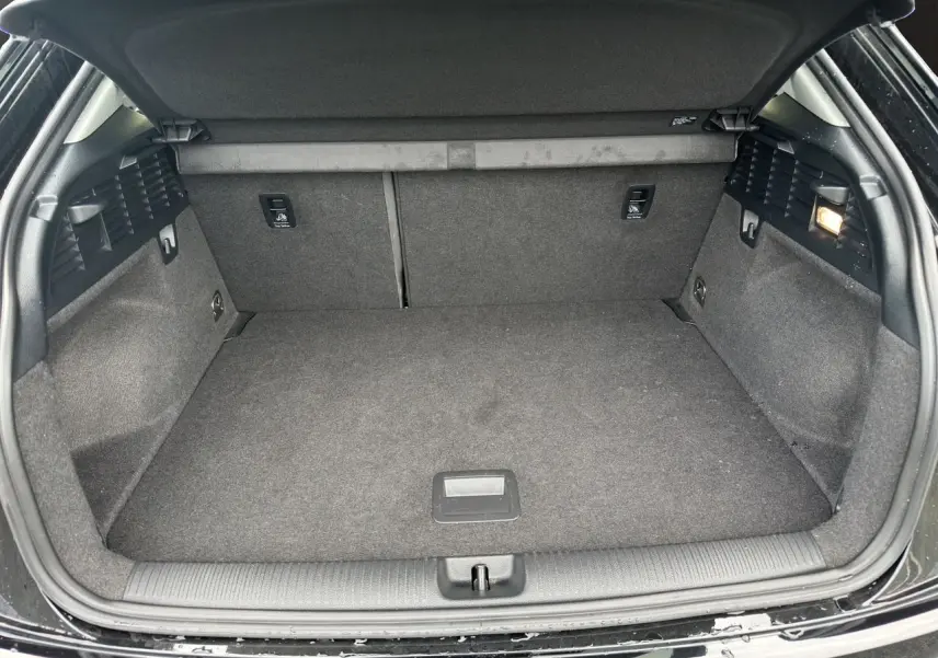Coffre ouvert d'un Audi Q2 noir Mito, vue intérieure montrant un espace de chargement propre et bien fini.