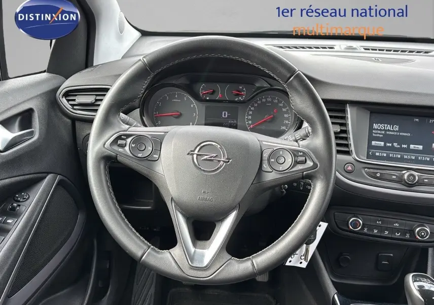 Vue centrée sur le volant cuir d'une Opel Crossland X gris pierre de lune, tableau de bord et écran multimédia visibles.