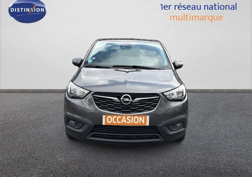 Vue avant d'une Opel Crossland X gris pierre de lune métal avec calandre noire et phares LED allumés.