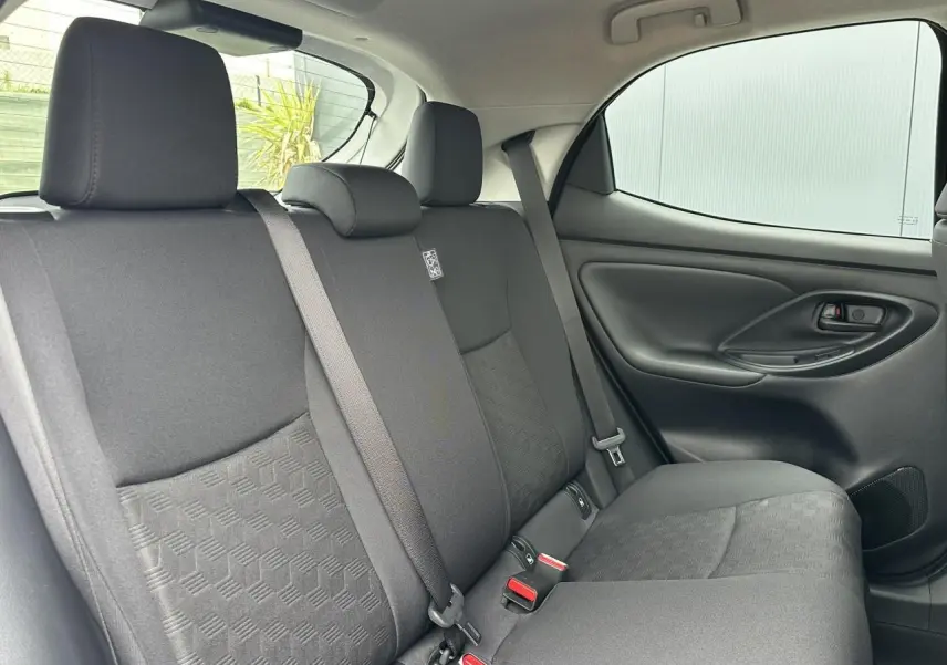Vue intérieure côté droit des sièges arrière en tissu noir de la Toyota Yaris Hybride 2025 avec ceinture de sécurité et porte latéral.
