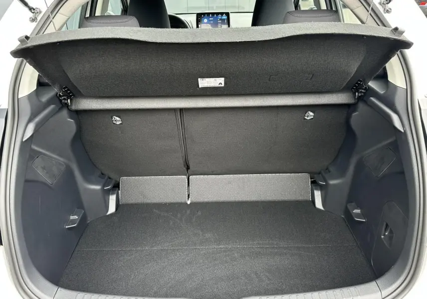 Coffre ouvert d'une Toyota Yaris blanche 2025, vue arrière montrant le double plancher et la banquette arrière noire.