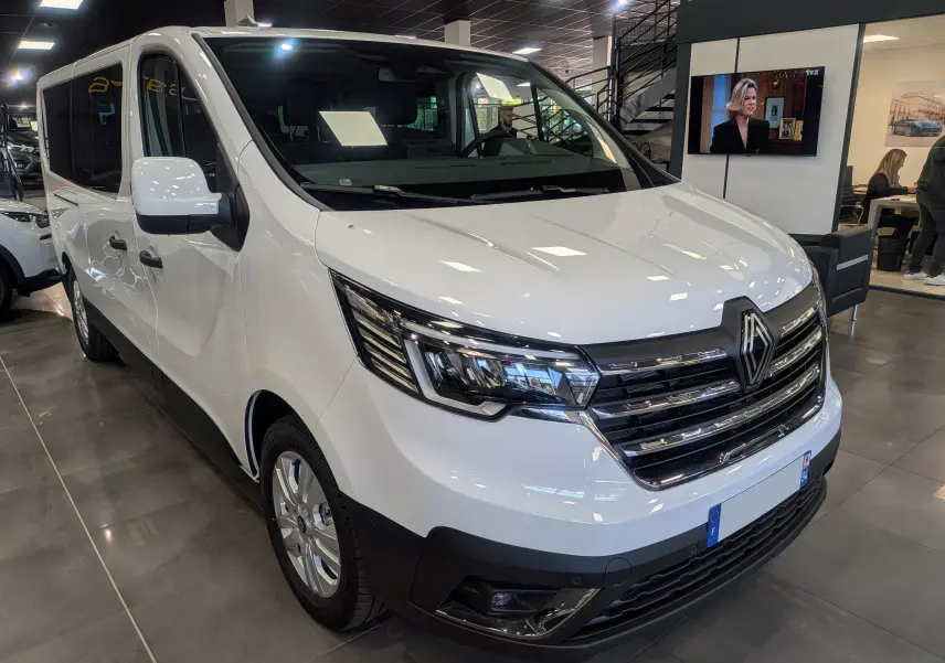 Renault Trafic Combi blanc glacier vu en 3/4 avant droit, mettant en valeur sa calandre chromée et ses phares LED.