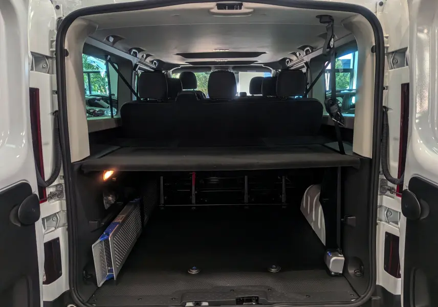 Vue arrière ouverte du Renault Trafic Combi blanc glacier montrant l'espace de chargement et les sièges arrière noirs.