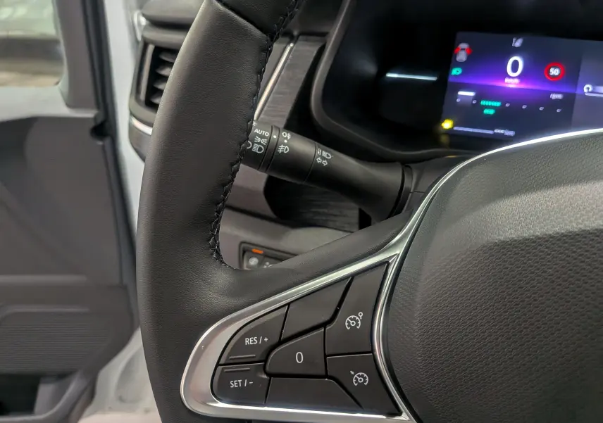 Gros plan sur le volant noir du Renault Trafic Combi blanc glacier avec tableau de bord digital allumé.