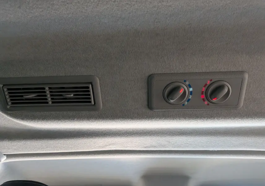 Détail du plafond intérieur du Renault Trafic Combi 2025 avec commandes de climatisation et bouche d'aération noire.