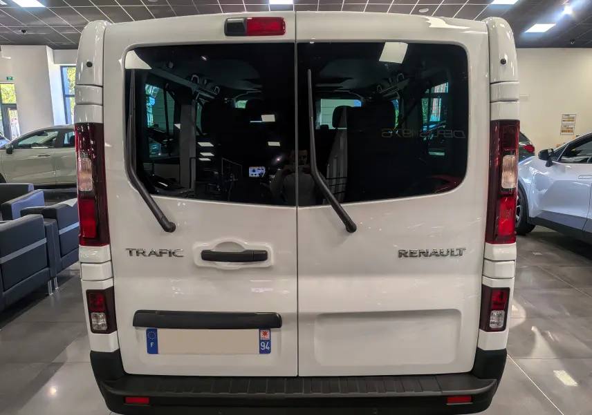 Vue arrière du Renault Trafic Combi blanc Glacier avec portes vitrées et essuie-glaces verticaux en showroom.