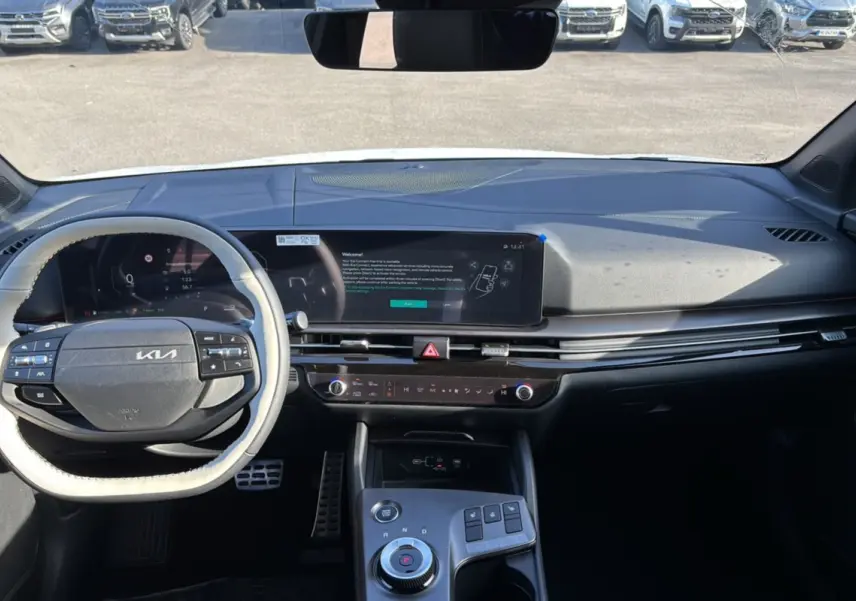 Vue intérieure du tableau de bord du Kia Sportage blanc nacré, avec volant cuir multifonctions et écran tactile panoramique.