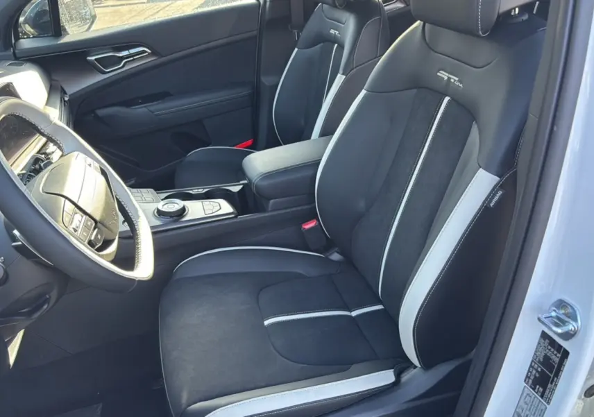 Vue intérieure côté conducteur du Kia Sportage 2026, sièges sport noirs et gris avec logo GT Line brodé.