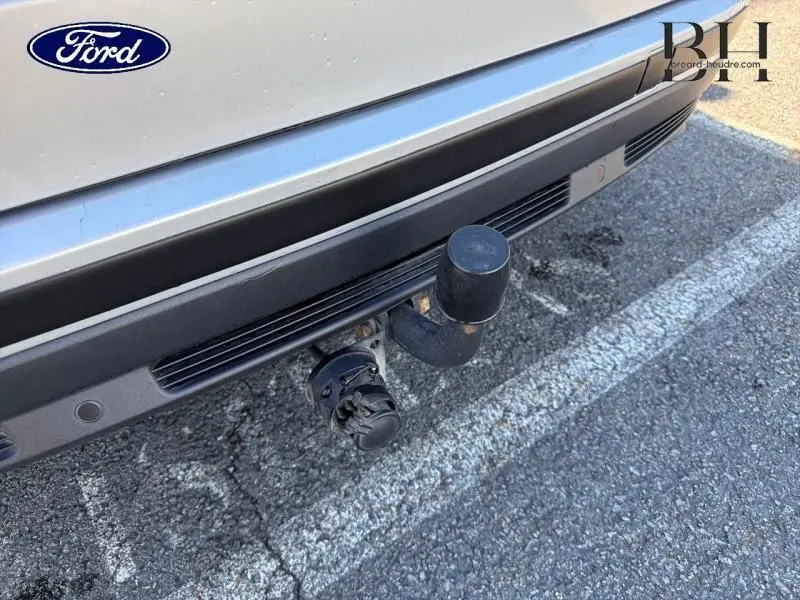 Gros plan sur l'attelage arrière noir d'un Ford S-MAX gris lunaire, avec prise électrique visible sur le pare-chocs.