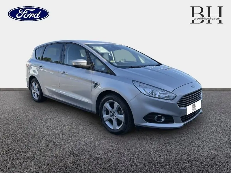 Ford S-MAX gris lunaire en 3/4 avant droit, avec calandre chromée et jantes alliage visibles.
