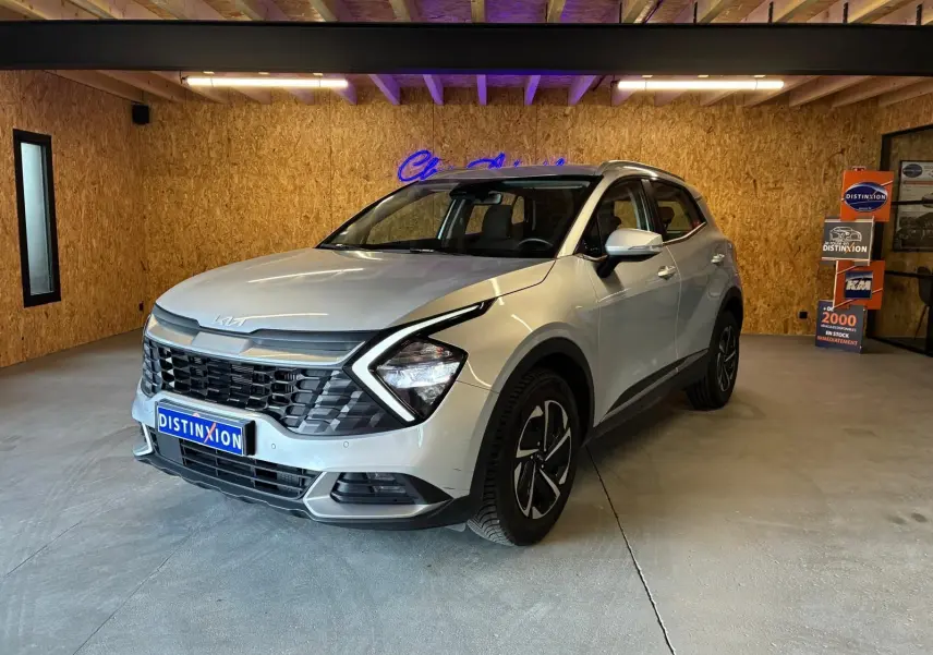 KIA Sportage hybride gris 2024 vu en 3/4 avant droit, avec calandre noire et jantes distinctives.