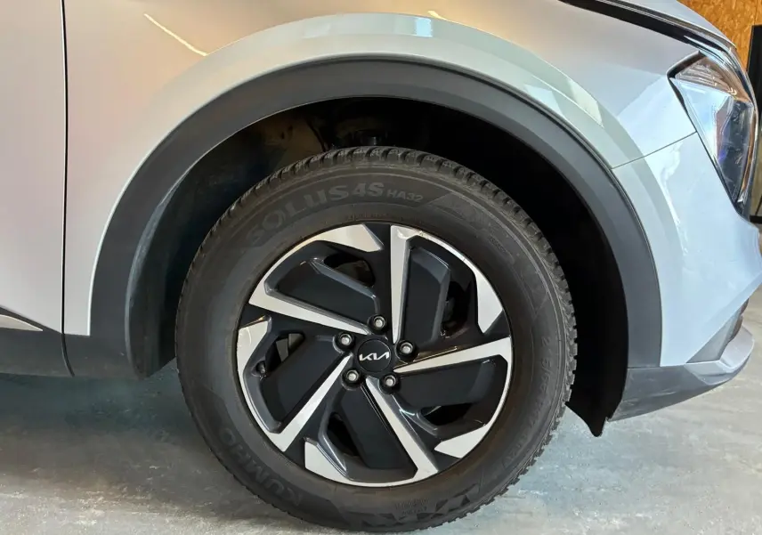 Gros plan sur la roue avant droite d’un Kia Sportage gris 2024, mettant en valeur la jante alliage bicolore au design moderne.