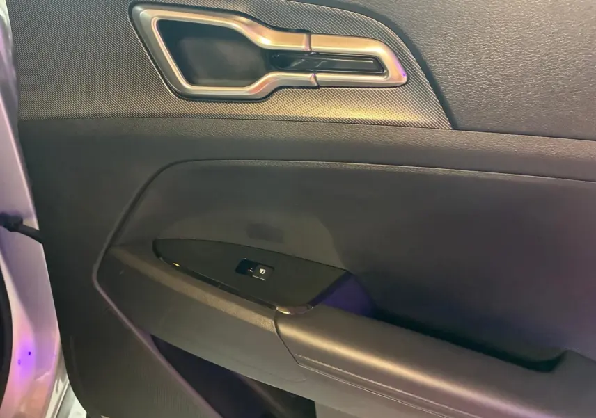 Gros plan sur la poignée intérieure et le panneau de porte côté gauche du KIA Sportage gris hybride 2024.