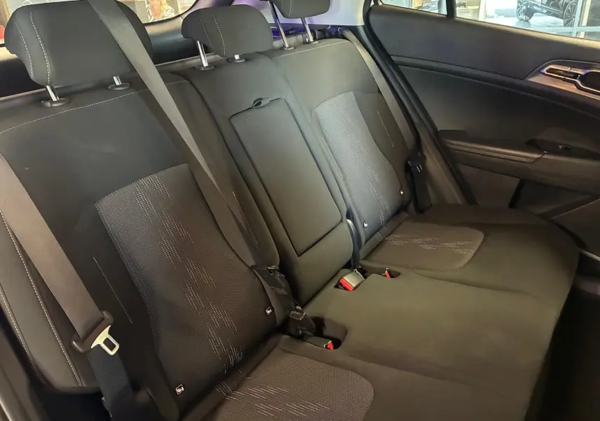 Vue intérieure des sièges arrière en tissu noir du Kia Sportage hybride 2024, avec ceinture de sécurité et accoudoir central rabattable.