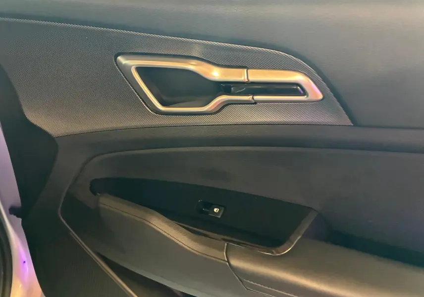 Détail de la poignée intérieure et commande de fenêtre côté gauche du KIA Sportage hybride gris 2024.