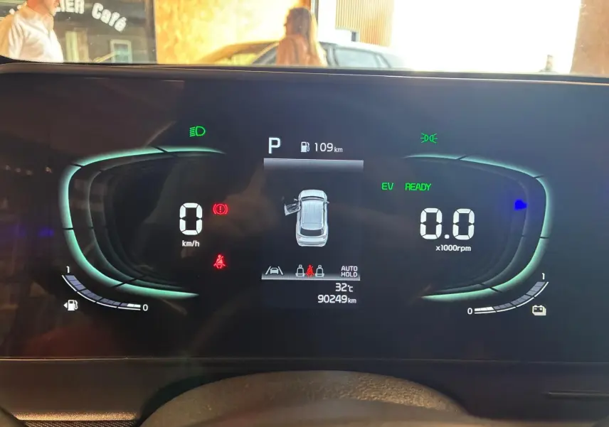 Tableau de bord numérique du Kia Sportage hybride 2024, affichage central avec vitesse, régime et autonomie, vue frontale intérieure.