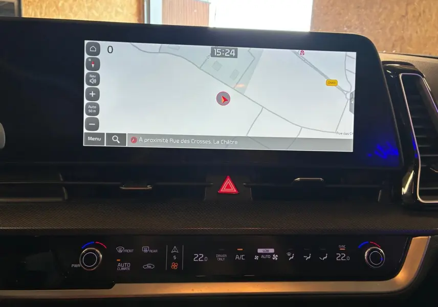 Vue intérieure du tableau de bord du Kia Sportage 2024 hybride, avec écran tactile de navigation et commandes climatisation.