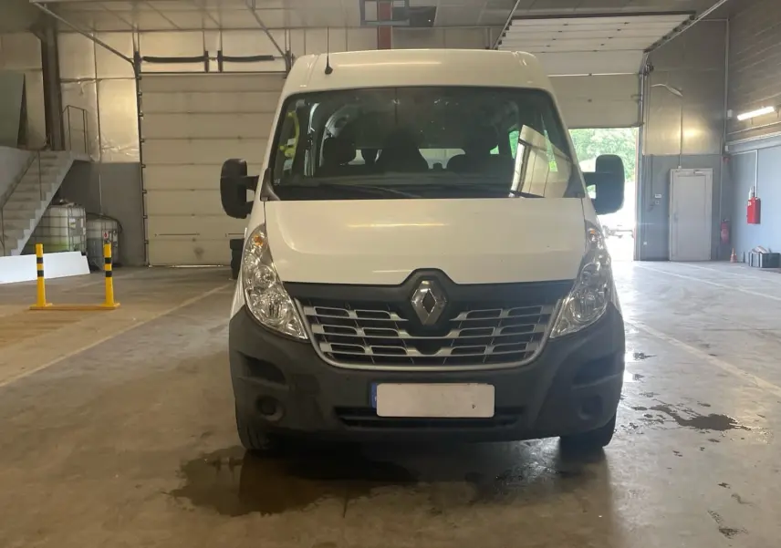 Vue de face d’un Renault Master blanc stationné en intérieur, avec calandre noire et grands rétroviseurs latéraux.