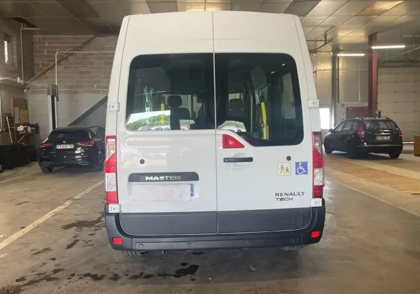 Vue arrière du Renault Master blanc TPMR avec rampe et stickers d’accessibilité, stationné en intérieur.