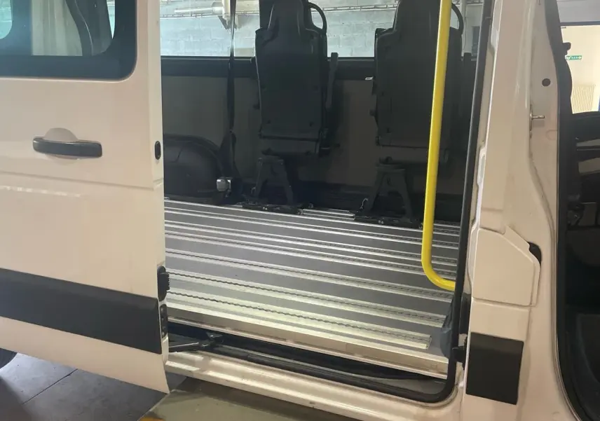 Vue latérale gauche du Renault Master blanc 2019 avec porte coulissante ouverte et sièges adaptés pour fauteuils roulants.