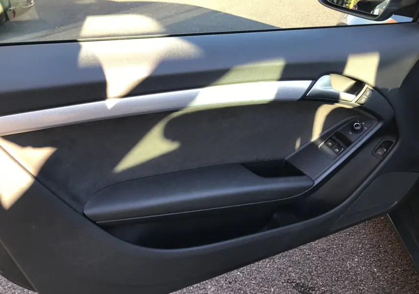 Panneau intérieur côté gauche de l'Audi A5 gris dauphin, avec commandes de vitres et poignée argentée.