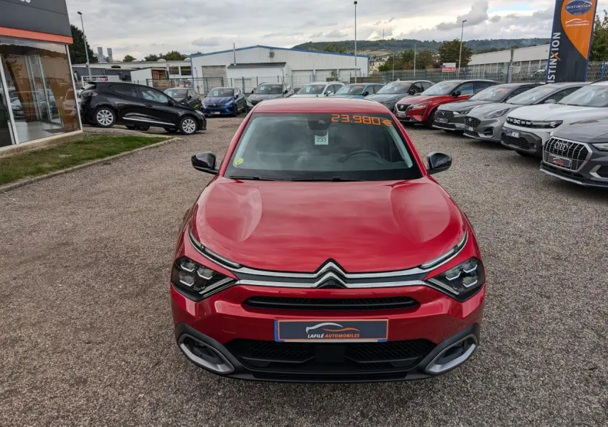 Vue avant d'une Citroën C4 rouge foncé 2024 avec calandre chromée et prix affiché sur pare-brise