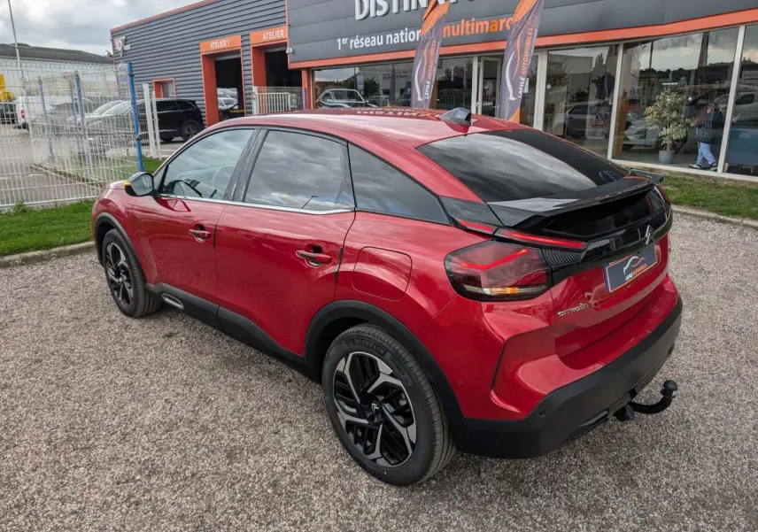 Vue 3/4 arrière droite d'une Citroën C4 rouge foncé avec attelage col de cygne et jantes alliage noires.