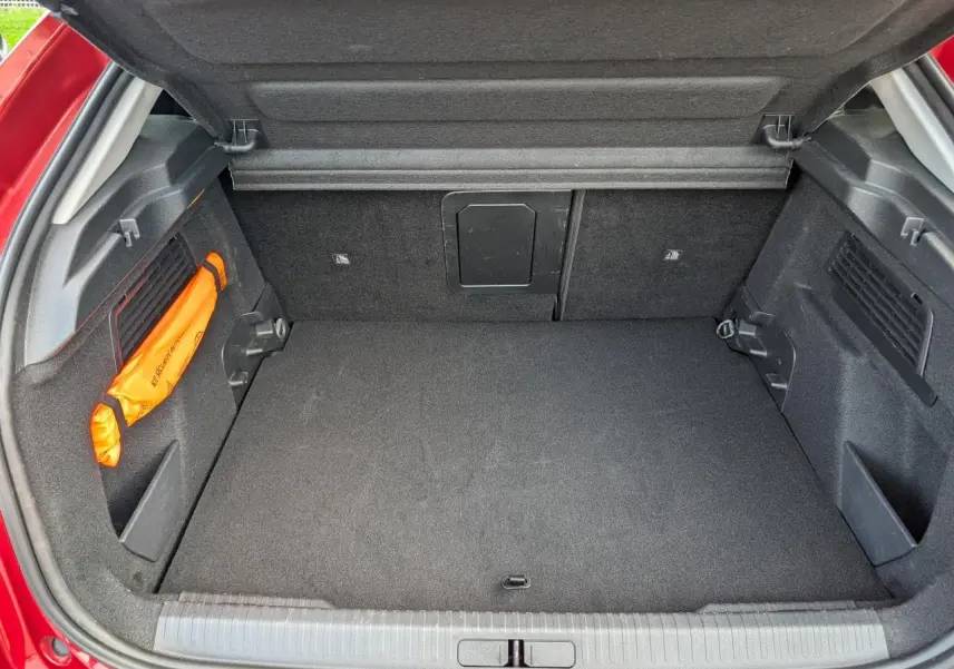 Coffre ouvert vu de l'arrière d'une Citroën C4 rouge foncé, espace de chargement propre et bien agencé.