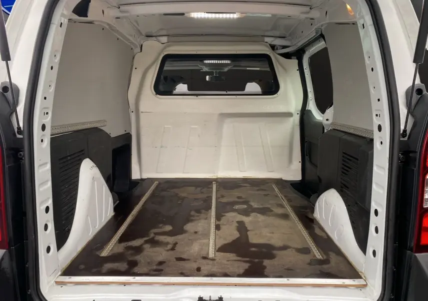 Vue intérieure arrière du Citroën Berlingo blanc 2018, montrant l’espace de chargement vide avec sol usé.