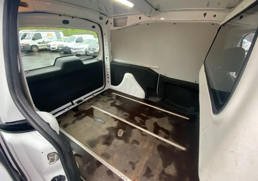 Vue intérieure arrière du Citroën Berlingo blanc 2018, montrant l’espace de chargement vide avec plancher usé.