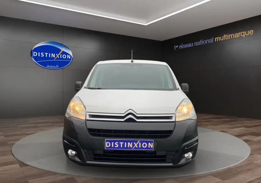 Vue de face du Citroën Berlingo blanc 2018 avec pare-chocs noir et phares allumés dans un showroom.