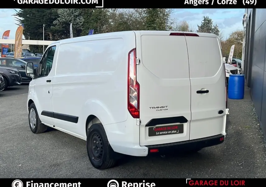 Vue 3/4 arrière droite d'un Ford Transit Custom blanc stationné, avec portes arrière fermées et jantes acier noires.