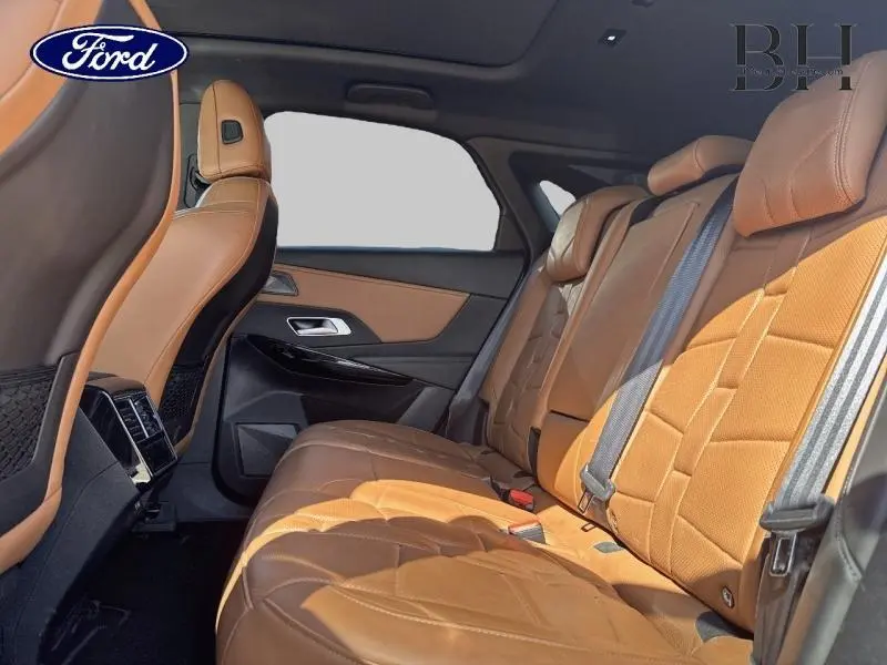 Vue intérieure arrière droite montrant les sièges en cuir brun Alezan avec toit ouvrant panoramique visible.