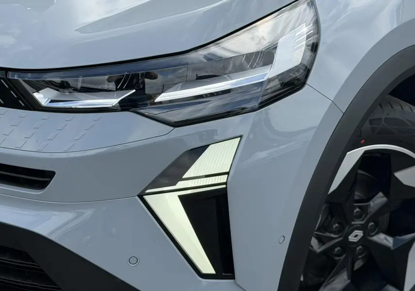 Gros plan sur l'avant droit gris Rafale du Renault Captur 2026, mettant en valeur les phares LED et la jante aluminium noire.