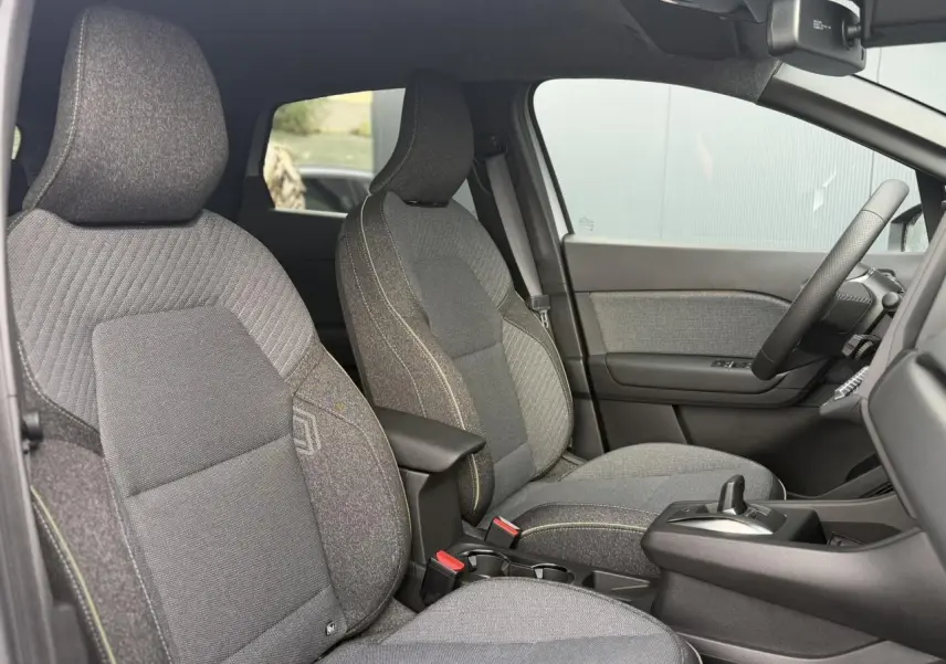 Vue intérieure côté droit du Renault Captur 2026, montrant les sièges tissu gris avec coutures contrastées et console centrale.
