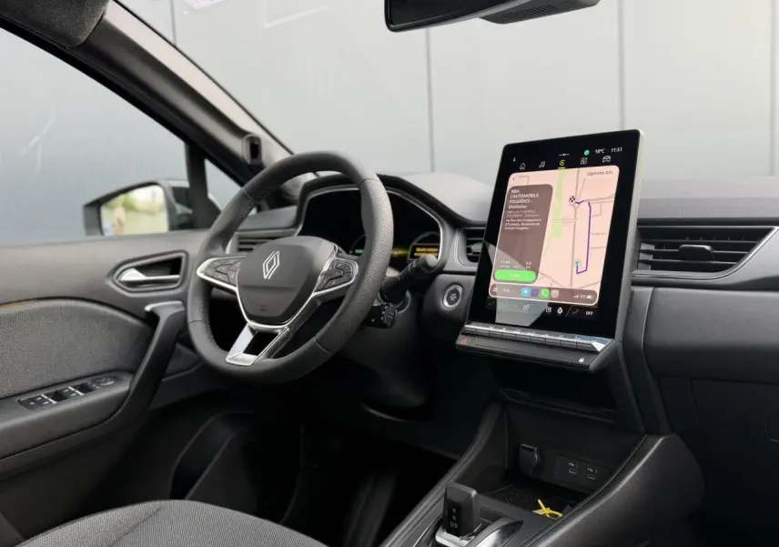 Vue intérieure côté conducteur du Renault Captur 2026, tableau de bord noir avec écran tactile vertical et volant multifonction.