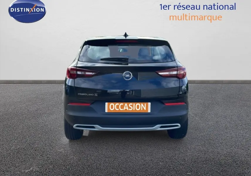 Vue arrière d'un Opel Grandland X noir diamant métal avec logo et feux arrière allongés, sur fond neutre.