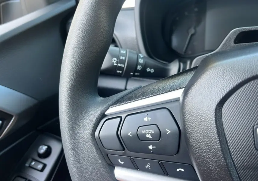 Gros plan sur les commandes multimédia au volant du pick-up Isuzu D-MAX 2026, intérieur noir.