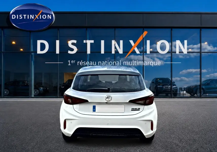 Vue arrière d'une MG3 1.5 hybrid 195 luxury blanche garée devant une vitrine avec logo Distinxion.