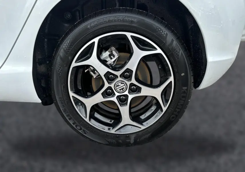 Gros plan sur la roue avant droite blanche d’une MG3 1.5 hybrid 195 luxury avec jante alu bicolore et logo MG central.