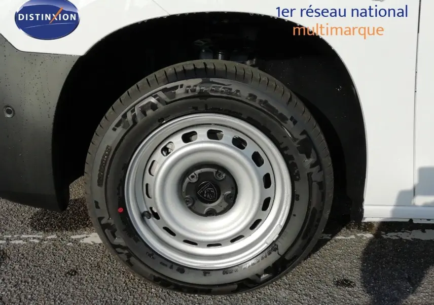 Gros plan sur la roue avant droite du Peugeot Partner blanc Kaolin, mettant en valeur la jante acier et le pneu noir.