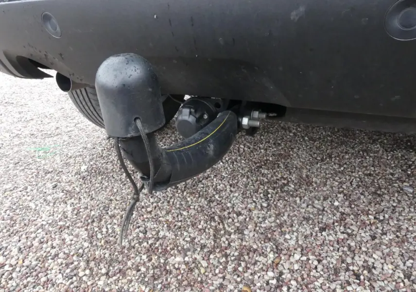 Gros plan sur l'attelage fixe noir sous le pare-chocs arrière d'un Dacia Duster noir 2023.